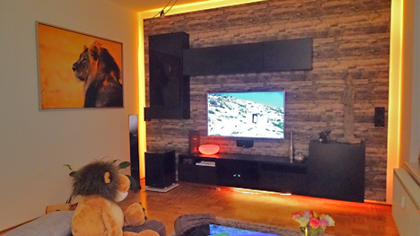 Ein fischer DUOPOWER-Projekt von trnd-Partner langesbuhm: Eine Wohnwand aus Holz mit indirekter Beleuchtung.